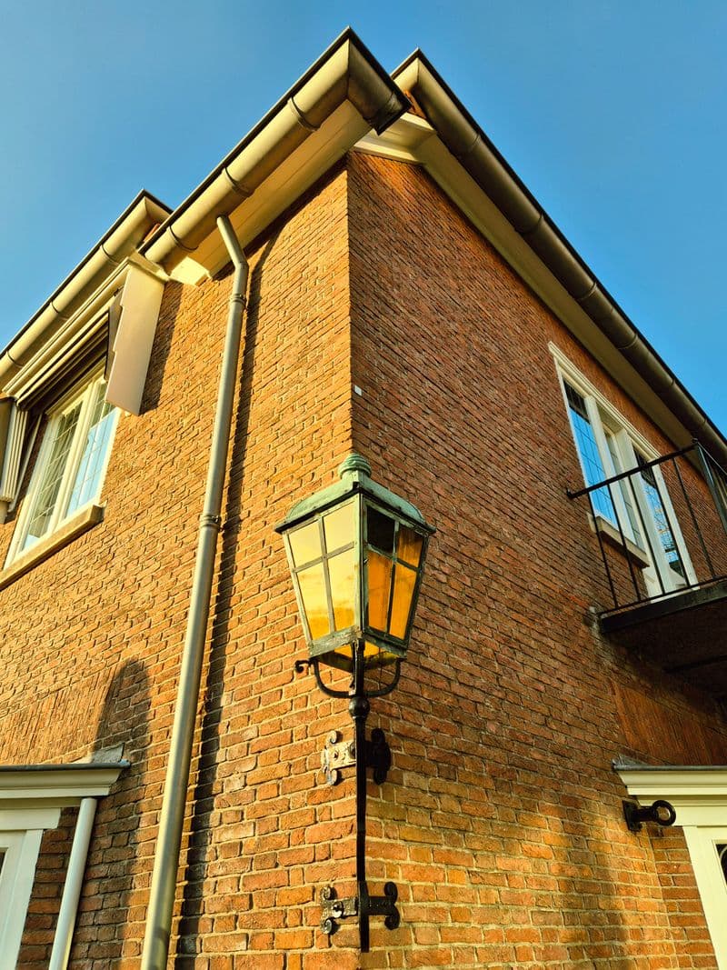 Corner of a brick house showing white fascias, soffits and guttering on roofline